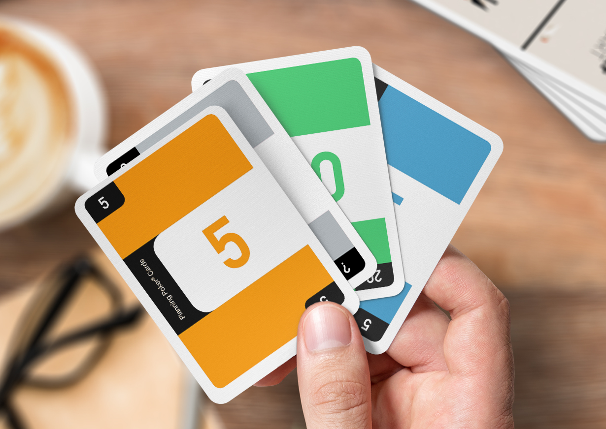 Eine Männerhand hält vier individuell gestaltete Planning Poker Karten zwischen dem Daumen und dem Zeigefinger